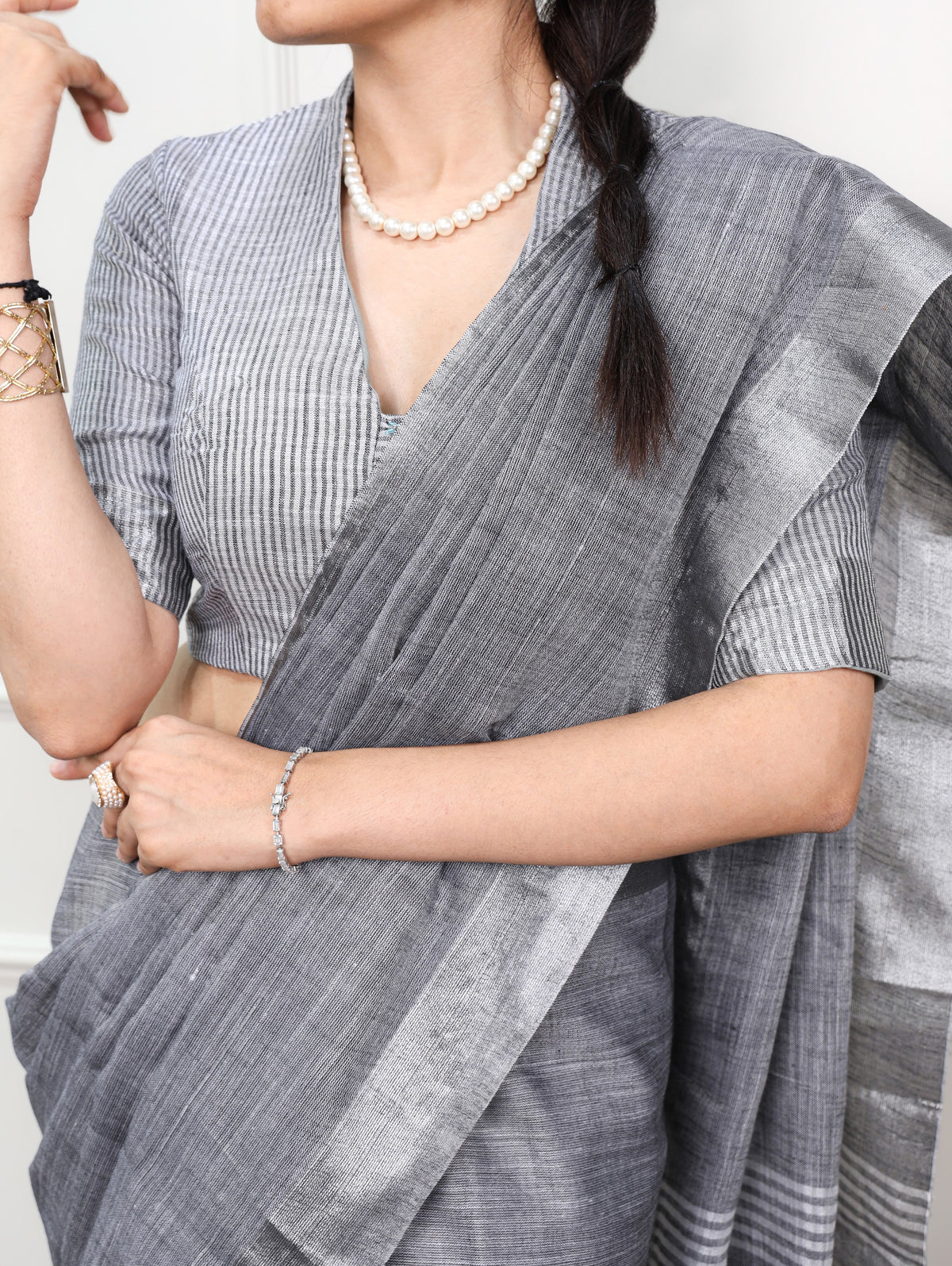 women wearing a gray saree with a white blouse, standing against a neutral background.